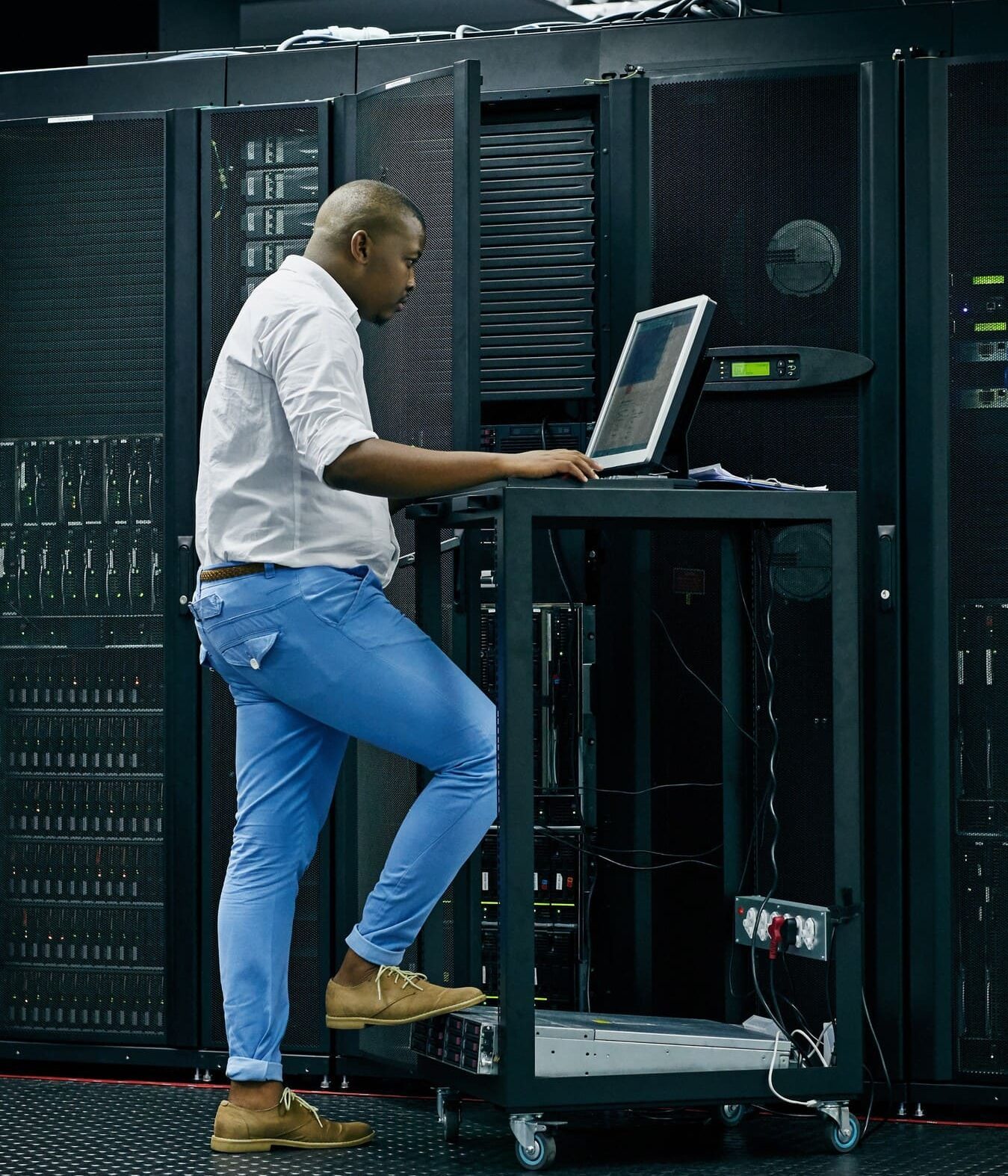 Hombre manipulando un ordenador en un lugar de servidores y paneles eléctricos.